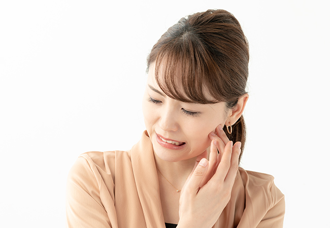 歯の痛みで頬をおさえる女性