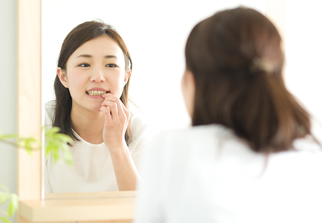 鏡で歯をチェックする女性